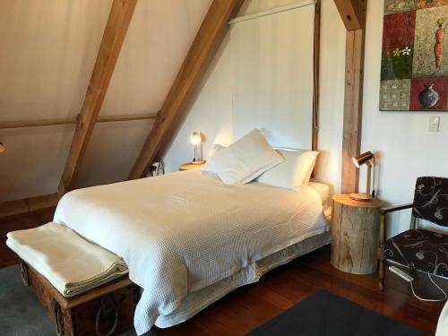 a bedroom with a large white bed with two lamps at Tree Hut Cottage in Masterton