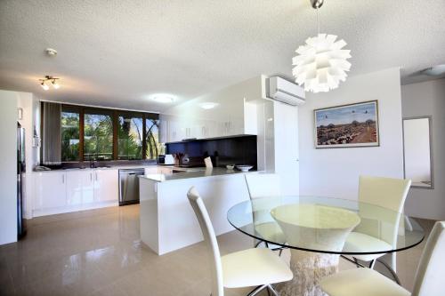 a kitchen and dining room with a glass table and chairs at Gemini Resort in Caloundra