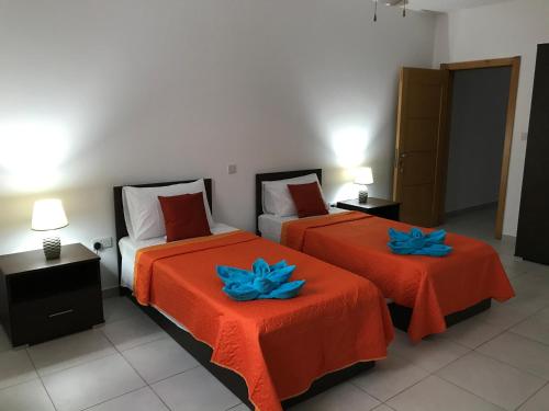 two beds in a room with two blue flowers on them at Ocean Pearl Apartment no4 in St Paul's Bay