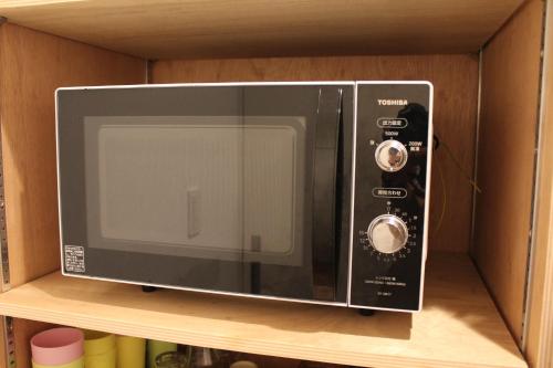 a microwave oven sitting on top of a shelf at plat hostel keikyu haneda home in Tokyo