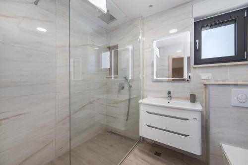 a bathroom with a shower and a sink and a mirror at Delux Apartments Sunset Beach in Promajna