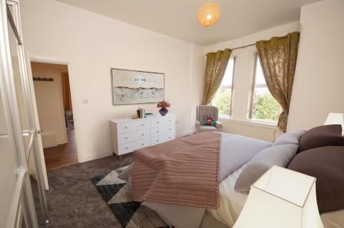 a bedroom with a bed and a dresser and a window at Grosvenor Lodge Birkdale in Southport