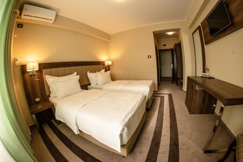 a hotel room with two beds and a desk at Hotel McPietroasa in Haleş