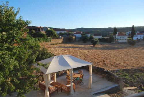 a table and chairs under an umbrella on a field at Casa dos Primos in Muxagata