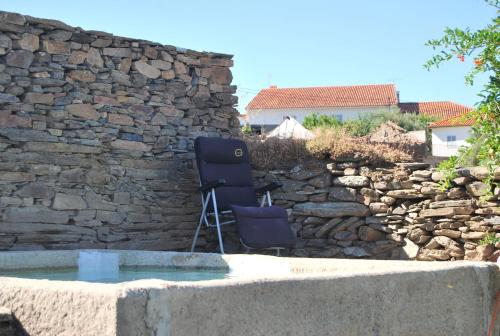 a stone wall with two chairs in a yard at Casa dos Primos in Muxagata