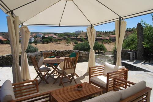 a patio with a table and chairs under a tent at Casa dos Primos in Muxagata