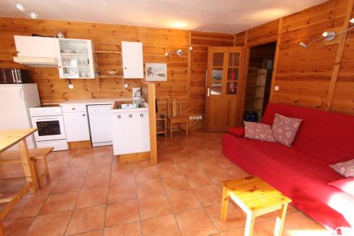 a living room with a red couch and a kitchen at Le Leyrier Hameau des Chazals Nevache Hautes Alpes in Névache