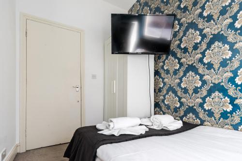 a room with two beds and a tv on the wall at City Rooms in London