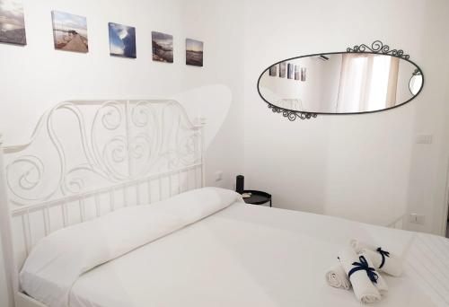 a white bedroom with a white bed and a mirror at La casa del pesciolino (into the lagoon) - The little fish house (into the lagoon) in Chioggia