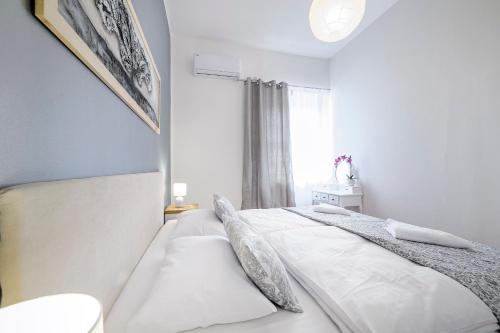a bedroom with a bed with white sheets and a window at Hostel Globo in Šibenik