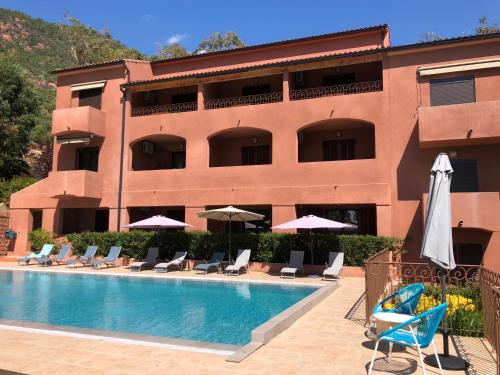 a hotel with a swimming pool with chairs and umbrellas at Hotel Corsica - Porto Corse in Porto Ota