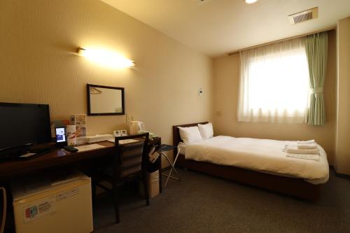 a hotel room with a bed and a desk with a computer at Hotel Green Arbor in Sendai