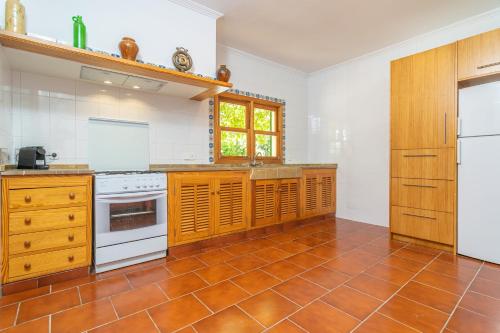 a kitchen with white appliances and a brown tile floor at Can Moscari in Inca