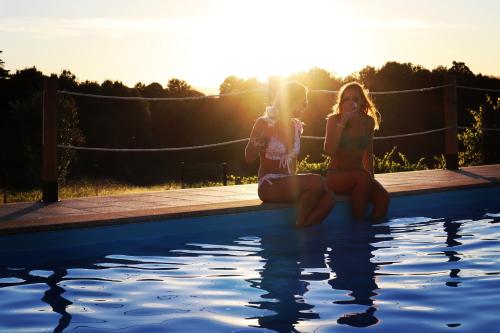 two girls sitting next to a swimming pool at Quinta de Real in Valença