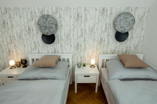 2 Betten in einem Zimmer mit 2 Tischen und 2 Platten an der Wand in der Unterkunft L&P Appartement Klagenfurt in Klagenfurt am Wörthersee