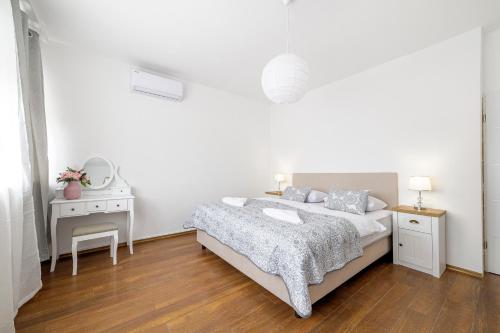 a white bedroom with a bed and a desk at Hostel Globo in Šibenik