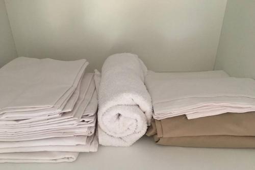 a bed with a stack of sheets and a towel at Anastasias Cottage in Nea Irakleia
