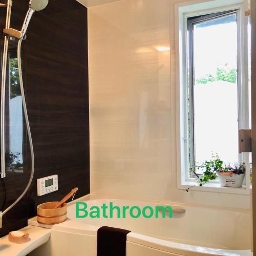 a bathroom with a shower and a sink and a window at ガーデンハウス Mako Land in Toyama