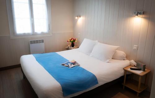 ein Schlafzimmer mit einem großen weißen Bett und einem Fenster in der Unterkunft Hotel Du Port in Concarneau