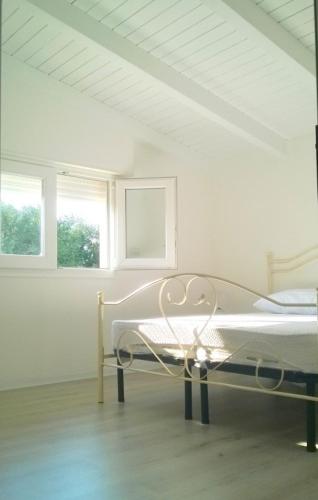 a white room with a bed and two windows at Dimora Arnesano in Torre Lapillo