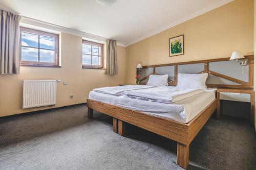a bedroom with a large bed and two windows at Hotel Resort Relax in Dolní Vltavice