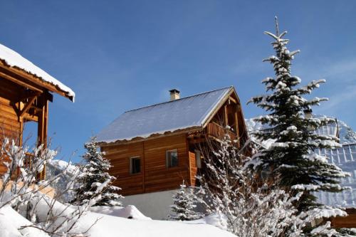une cabane en rondins dans la neige avec un arbre de Noël dans l'établissement Le Sorè Hameau des Chazals Nevache Hautes Alpes, à Névache