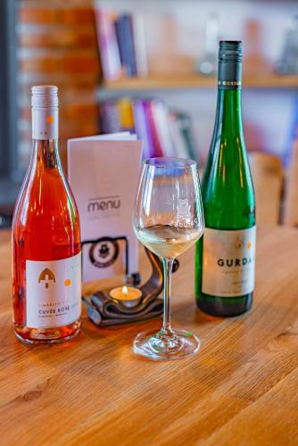two bottles of wine and a glass on a table at Žabinec - penzion, vinotéka in Kurdějov