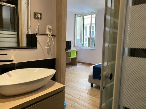 a bathroom with a white sink and a room at Hotel Genziana in Genova