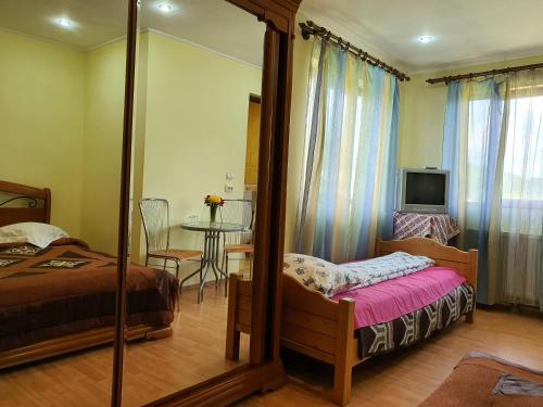 a bedroom with a bed and a mirror and a table at Casa Carpati in Zărneşti