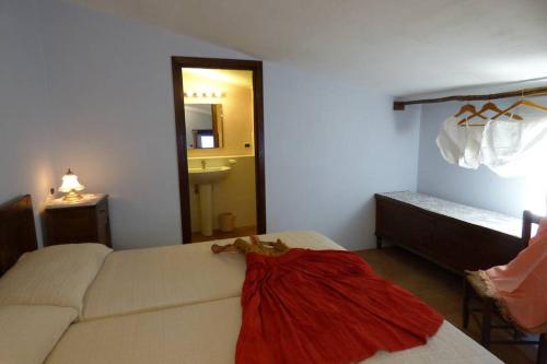 ein Zimmer mit einem Bett mit einem roten Kleid darauf in der Unterkunft Il Nibbio - La Casa del Vasaio in Morano Calabro