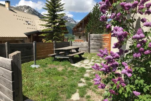 a picnic table in a yard with purple flowers at Le Pignotto Hameau des Chazals Nevache Hautes Alpes in Névache