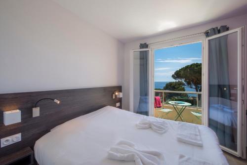 a bedroom with a bed and a view of the ocean at Hôtel-Club du Domaine d'Aiguebelle, USSIM Vacances in Le Lavandou