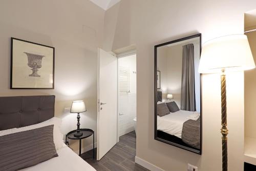 ein Schlafzimmer mit einem Spiegel, einem Bett und einer Lampe in der Unterkunft RESIDENZA VITTORIA Roma in Rom
