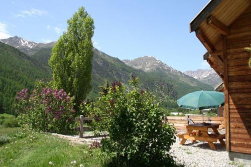 a picnic table and an umbrella next to a cabin at L'Elva Hameau des Chazals Nevache Hautes Alpes in Névache