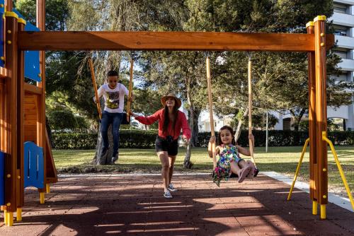 a boy and a girl playing frisbee in a park at Pestana D. João II Beach & Golf Resort in Alvor