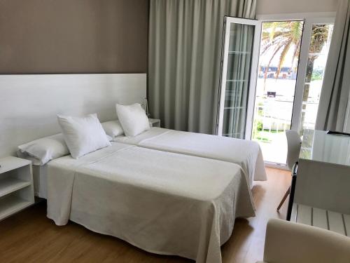 a hotel room with two beds and a large window at Hotel Nuevo Vichona Spa 3 estrellas Superior in Sanxenxo