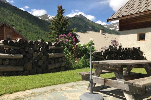 a picnic table and a fence with mountains in the background at Le Taquo Hameau des Chazals Nevache Hautes Alpes in Névache