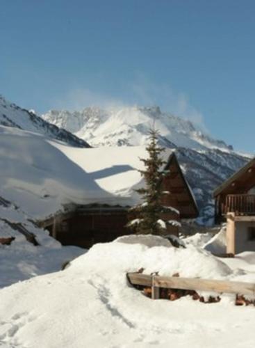 a snow covered mountain with a cabin and a tree at Le Taquo Hameau des Chazals Nevache Hautes Alpes in Névache
