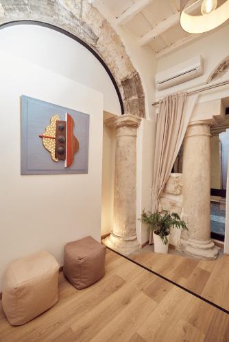 a living room with a large room with columns and a painting at L' Hôtellerie Easy Suites in Palermo