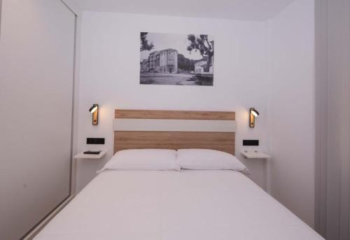 a bedroom with a large white bed with two lights at APARTAMENTOS LLAMIEVA in Posada de Llanes