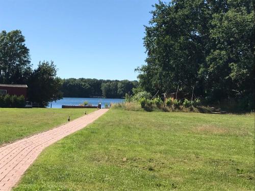 um caminho de tijolos ao lado de um campo gramado ao lado de um lago em Haus am See Altjuehrden em Varel