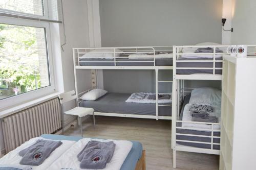 a room with three bunk beds and a window at Flensbed Hotel & Hostel in Flensburg