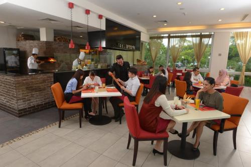 a group of people sitting at tables in a restaurant at Holiday Inn Melaka by IHG in Melaka