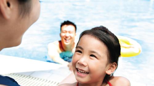 a young girl smiling at a group of people in a pool at Holiday Inn Melaka by IHG in Melaka