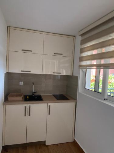 a kitchen with white cabinets and a sink and a window at Apartments Boss in Budva