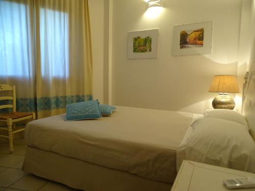 a bedroom with a bed and a lamp and a window at Hotel Mariposas in Villasimius