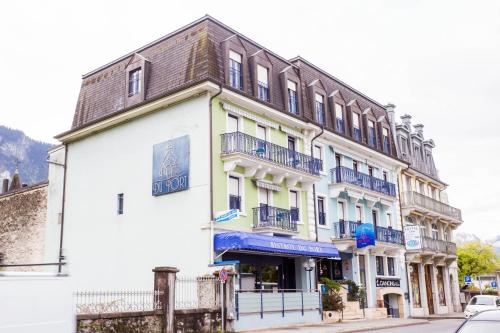 a white building with blue balconies on a street at Hôtel du Port in Villeneuve