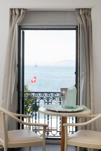 a table with a laptop on a balcony with the ocean at Hôtel du Port in Villeneuve