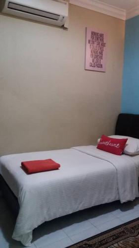 a bed with two red pillows on top of it at Manja Inn, Paka in Paka