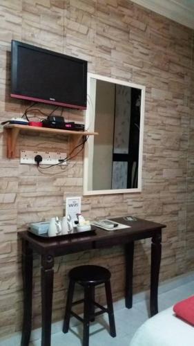 a desk with a mirror and a television on a wall at Manja Inn, Paka in Paka
